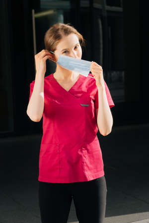 Portrait of a young female doctor putting on a medical mask with gloves.の写真素材
