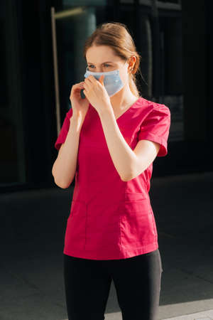 Portrait of a young female doctor putting on a medical mask with gloves.の写真素材