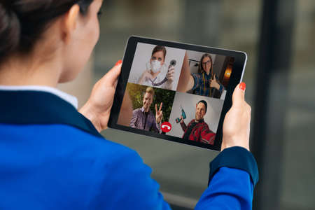 female hands hold a tablet while talking via video link with specialist friends.の写真素材