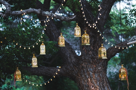 Night wedding ceremony with a lot of candles and vintage lamps on big tree
