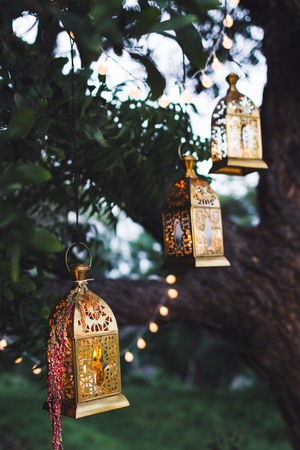 Night wedding ceremony with a lot of candles and vintage lamps on big treeの写真素材