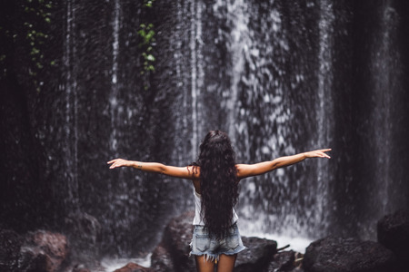 Beautiful brunette woman enjoying near waterfall