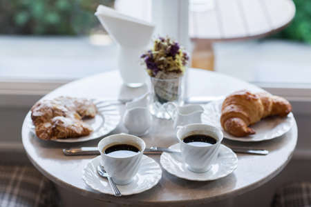 Frehcn breakfast with fresh croissants and hot coffee on white table