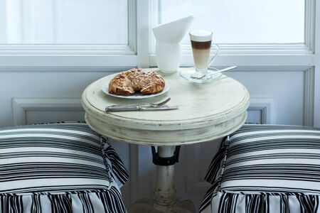 Delicious almond croissant on vintage white table with hot coffee latteの写真素材