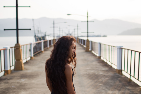 Woman with long black hair walking on empty bridge in the morningの写真素材