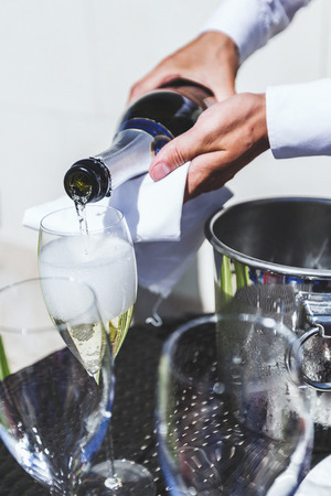 The waiter pours champagne into glassesの写真素材