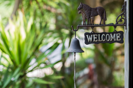 Vintage welcome plate with horses and bell in the gardenの写真素材