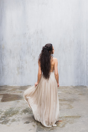 Bride with long black hair in the studio, a photo from the backの写真素材