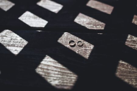 Wedding rings on wood texture with shadows