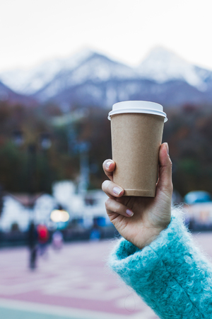 Girl's hand holding a cup of warming beverage with Mountain Viewの写真素材
