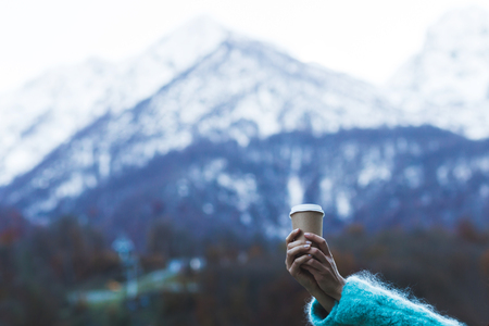 Girl's hand holding a cup of warming beverage with Mountain Viewの写真素材