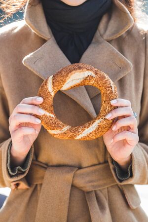 Beautiful woman holds a traditional Turkish simit in handsの写真素材