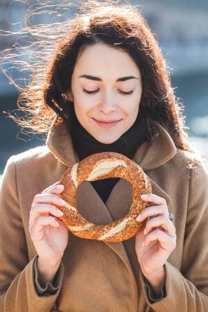 Beautiful woman holds a traditional Turkish simit in hands