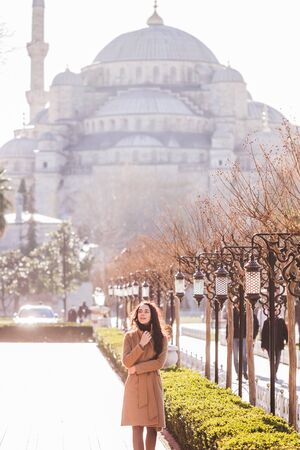 Woman in beige coat walks in the area near the Blue Mosque at beautiful sunny weatherの写真素材