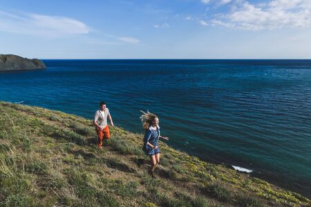 Man and woman running by the beach in warm sunny weather in springの写真素材
