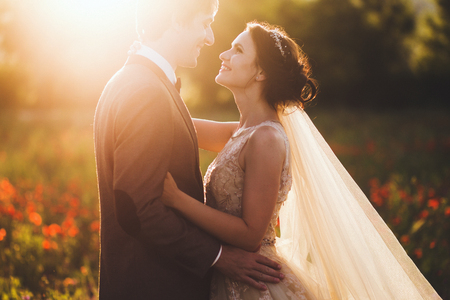 Sunshine portrait of happy bride and groom outdoor in nature location at sunset. Warm summertimeの写真素材