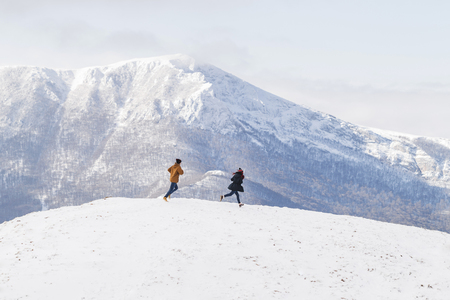 People having fun and running in mountains on the background of high snow-capped peaksの写真素材