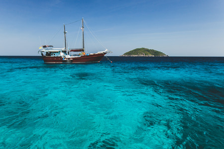 Tourist diving boat near island shore with turquoise clear transparent water. Idyllic view of Similan Islandsの写真素材