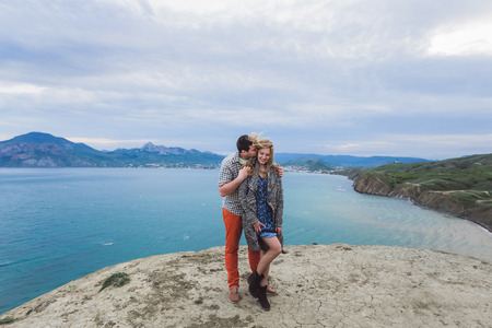 Couple on edge of cliff with incredible sea view. Joy, happiness and wind in hairの写真素材