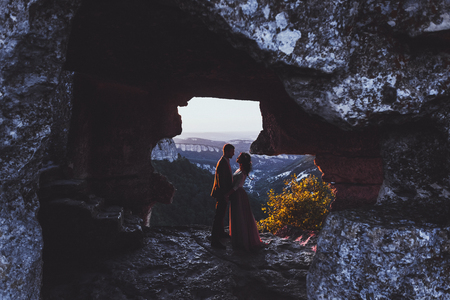 Wedding photo shoot at mountain Mangup in Crimea. Silhouette of loving couple newlyweds at sunset lightの写真素材