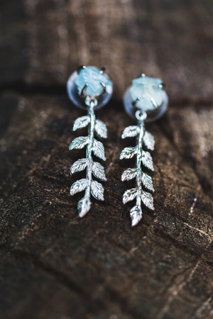 Silver earrings with blue stone on wooden background closeupの写真素材
