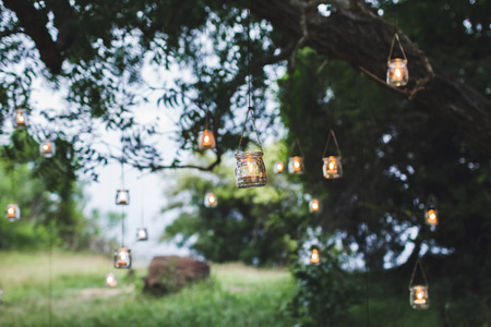 Night wedding ceremony with a lot of vintage lamps and candles on big treeの写真素材