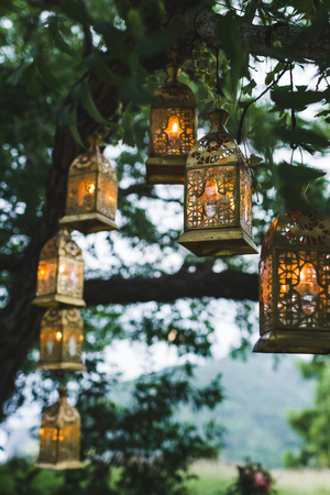 Night wedding ceremony with a lot of vintage lamps and candles on big treeの写真素材