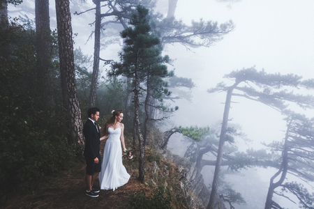 Wedding in a mysterious forest. Newlyweds walk in the mist, autumn moodの写真素材