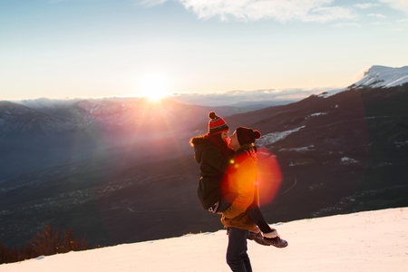 Young couple enjoying together. Having fun in snow at sunset in mountainsの写真素材