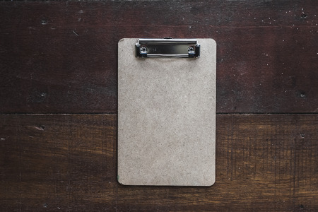 Vintage craft clipboard on dark brown wooden background. Empty space for text, sign or logoの写真素材