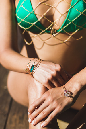 Details of luxury green swimsuit with golden chains on tanned slim women body. Fashion trends in Bali styleの写真素材