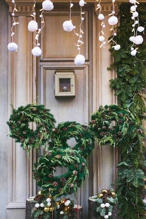 Facade decoration with christmas wreaths with fir branches and cones. Greeting arrangement on entrance with beautiful New Year toysの写真素材