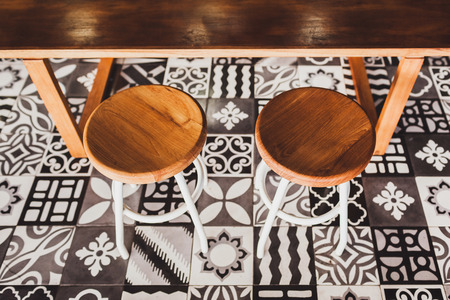 Modern wooden furniture in cafe on floor with black and white ornament tile. Two chairs, table, sofaの写真素材