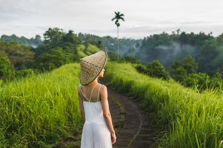 Young beautiful woman walking on Campuhan Ridge way of artists, in Bali, Ubud. Beautiful calm sunny morningの写真素材