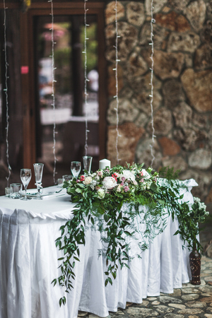 White wedding table decorated with green flowers arrangement, name cards, pink peony, white cutlery, rustic styleの写真素材