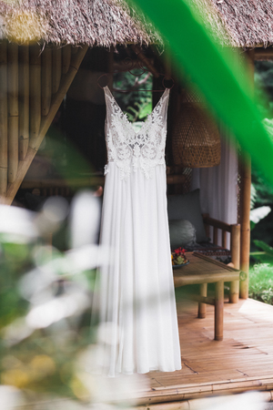 White wedding dress hanging on terrace of wooden rustic house in gardenの写真素材