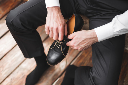 Man wearing brown leather classic shoes, black trousers and white shirt, business styleの写真素材