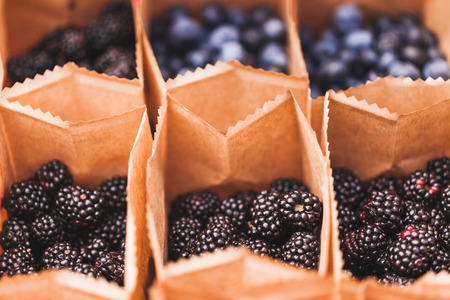 Fresh blackberry and blueberry in small craft paper boxes on wedding reception table, rustic style, summer moodの写真素材