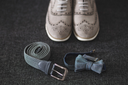 Male wedding set - classic leather shoes, belt and grey bow tie on dark-grey textureの写真素材