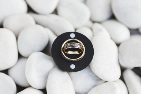 Wedding rings in round black box on white pebble stone backgroundの写真素材
