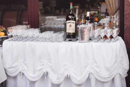 White table with lot of empty glasses and whisky bottle on stand. Wedding party receptionの写真素材