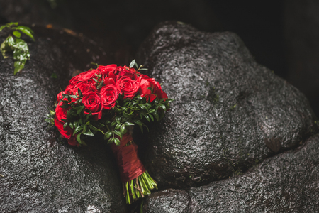 Classic wedding bouquet with red roses on dark stone backgroundの写真素材