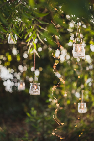 Night wedding ceremony with a lot of vintage lamps and candles on big treeの写真素材