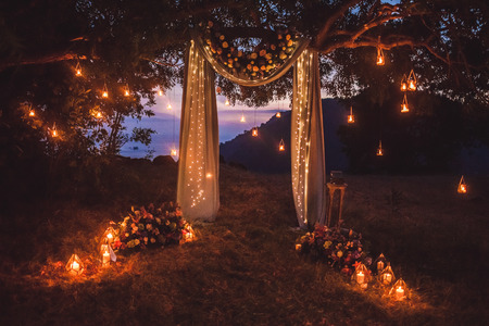 Night wedding ceremony with a lot of lights, candles, lanterns. Beautiful romantic shining decorations in twilightの写真素材