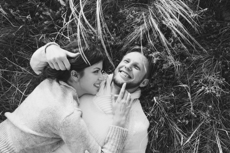 Happy young loving couple lying in feather grass, laughing and hugging, view from above. Black and white styleの写真素材