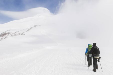ELBRUS REGION, RUSSIA - JUNE 25, 2017: Two tourists hiking to the top of mount Elbrus in Russia....