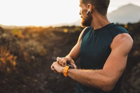 Athletic runner start training on fitness tracker or smart watch and looking forward on horizon....