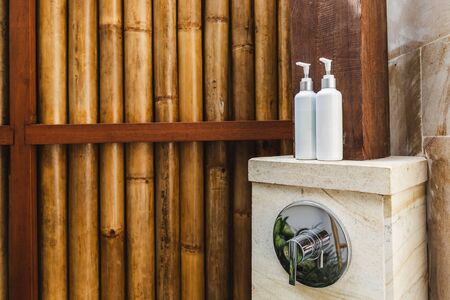 Two bottles of shampoo and shower gel in outdoor tropical shower on wooden bamboo background. Bali style. Eco concept.の写真素材
