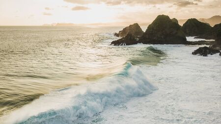 Sunset landscape with huge waves and mountain hills on horizon. Lombok island, Indonesiaの写真素材