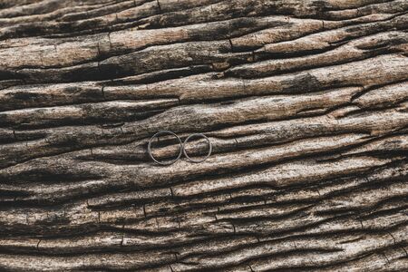 Two wedding rings on wooden brown texture background close upの写真素材